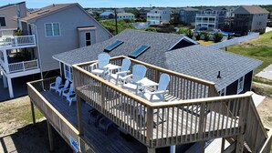 A wooden deck with white chairs and a table, overlooking a residential area with houses and a clear sky. - Semi-Oceanfront, 100 ft to beach access, Sun Decks, KH141, Blue Heaven (Kitty Hawk)