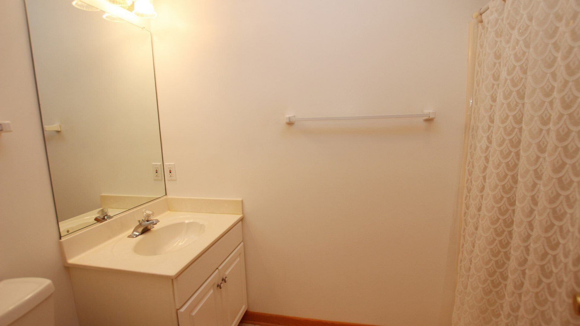 Une petite salle de bain avec un lavabo blanc, un miroir et un porte-serviettes.