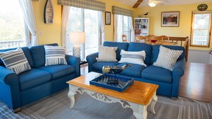 A cozy living room with two blue sofas, a wooden coffee table, and a bookshelf.