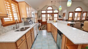 A kitchen with wooden cabinets, a marble countertop, and a tiled floor.