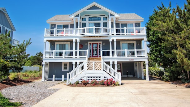 A two-story house with a front porch, a red door, and a staircase leading to the upper level. - Oceanside, Private Pool, Community Amenities, Hot Tub, VOH94, Knot A Problem (Corolla)