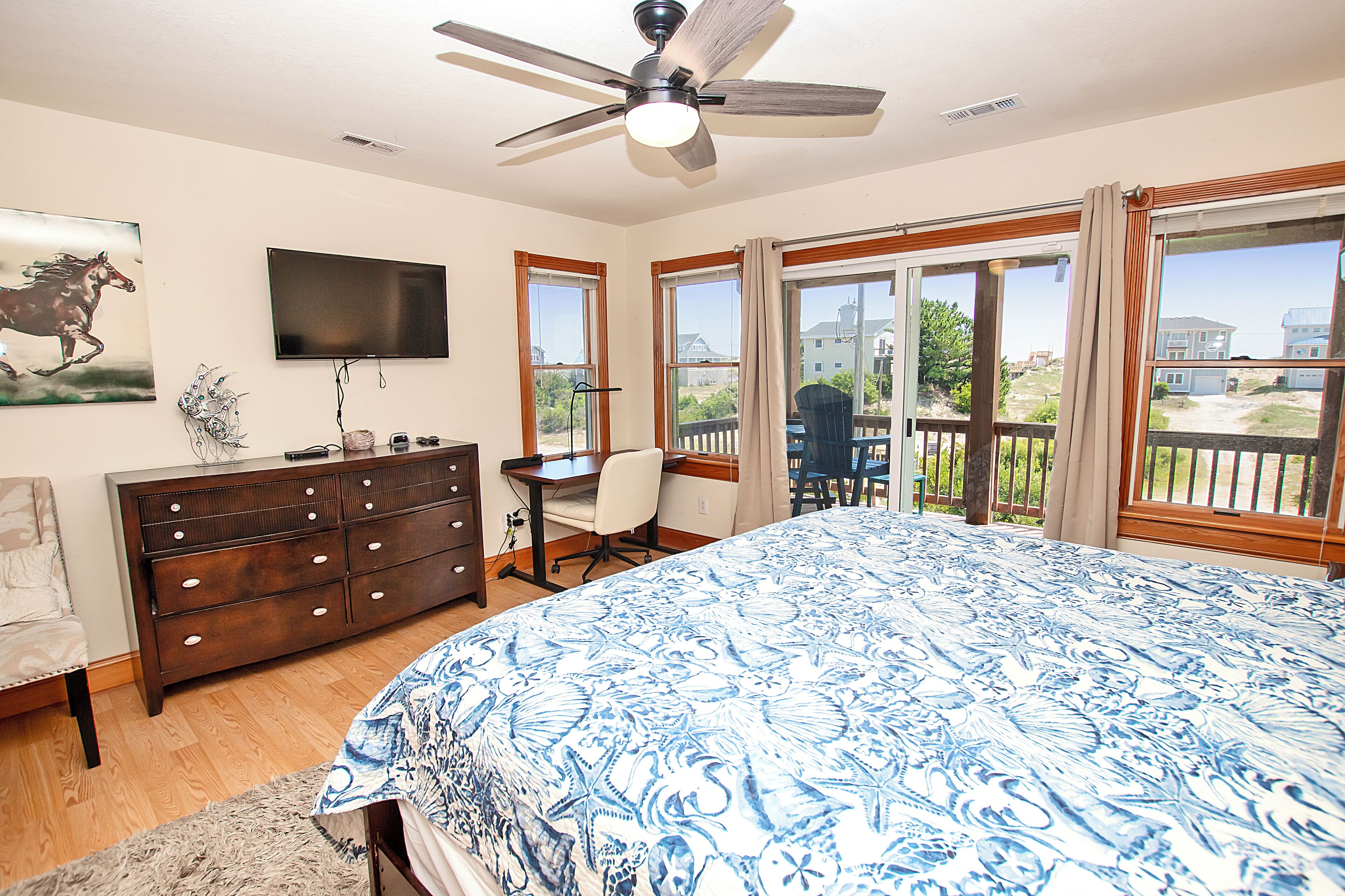 Une chambre dotée d’un grand lit, d’un bureau, d’une chaise, d’une commode, d’un téléviseur et d’un balcon avec vue.