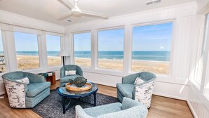 A sunlit room with large windows overlooking a beach, furnished with two armchairs and a coffee table. - OCEANFRONT, Ocean Views, Sun Decks, Close to Beach Access, SA112, The SandBar (Duck)