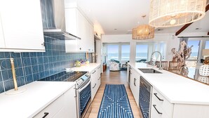 A modern kitchen with white cabinets, a blue patterned backsplash, and a blue and white rug. - OCEANFRONT, Ocean Views, Sun Decks, Close to Beach Access, SA112, The SandBar (Duck)