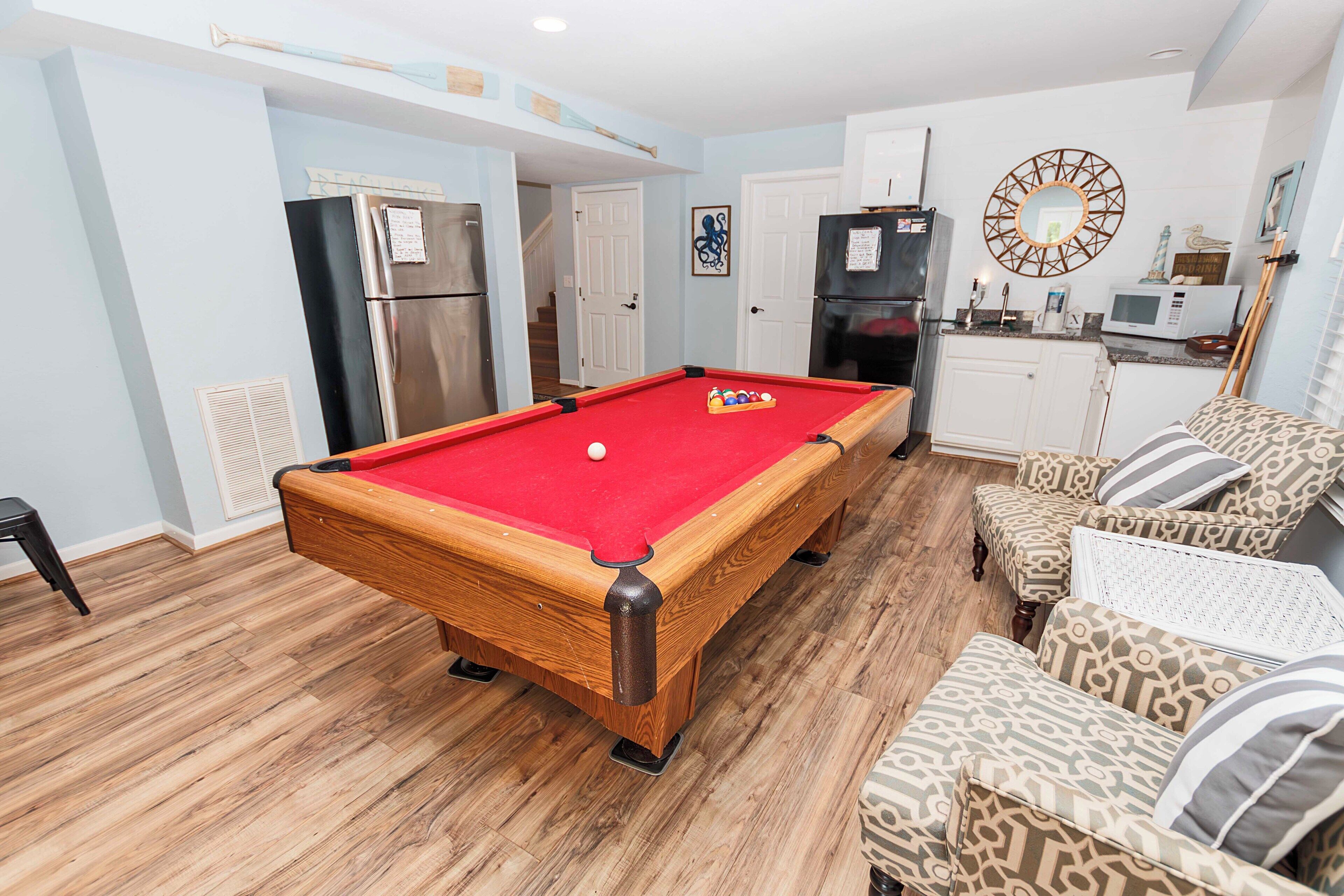 Une table de billard dans une pièce qui comprend un coin cuisine, une table à manger et des chaises à motifs.