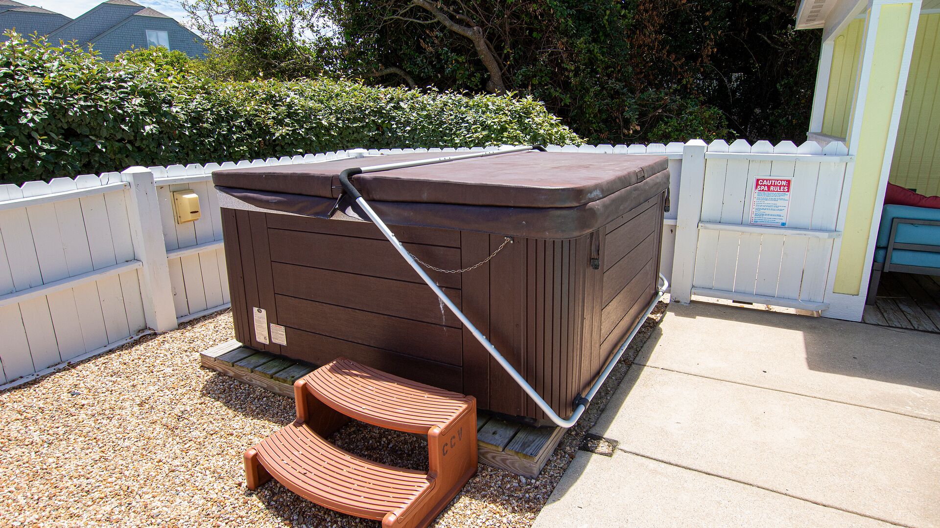 Een bubbelbad in een wellnessruimte met een houten terras en een waarschuwingsbord.