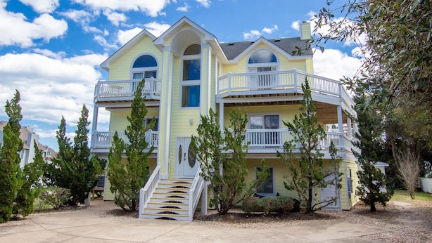 A two-story house with a balcony on the second floor, surrounded by trees. - Oceanside, Heated Pool, Poolside Pavilion, Hot Tub, 4, Relax Mom (Corolla)