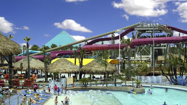 A water park with a large water slide, a pool area, and thatched umbrellas. - Bahama Breeze Canal Retreat • Dock, Fishing & Water Access • 3 Min. to Beach (Galveston)