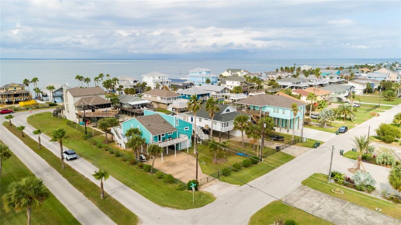 A residential area with houses, a road, and a body of water in the background.