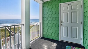 Une véranda avec vue sur l’océan, une porte blanche et un mur vert.