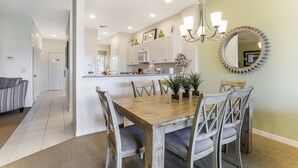 Un coin repas avec une table et des chaises en bois, un lustre et un grand miroir au mur.