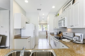 A modern kitchen with white cabinets, stainless steel appliances, and granite countertops.
