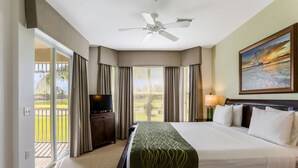 Une chambre d’hôtel avec un lit, une télévision, un ventilateur de plafond, un tableau et une vue sur l’extérieur.