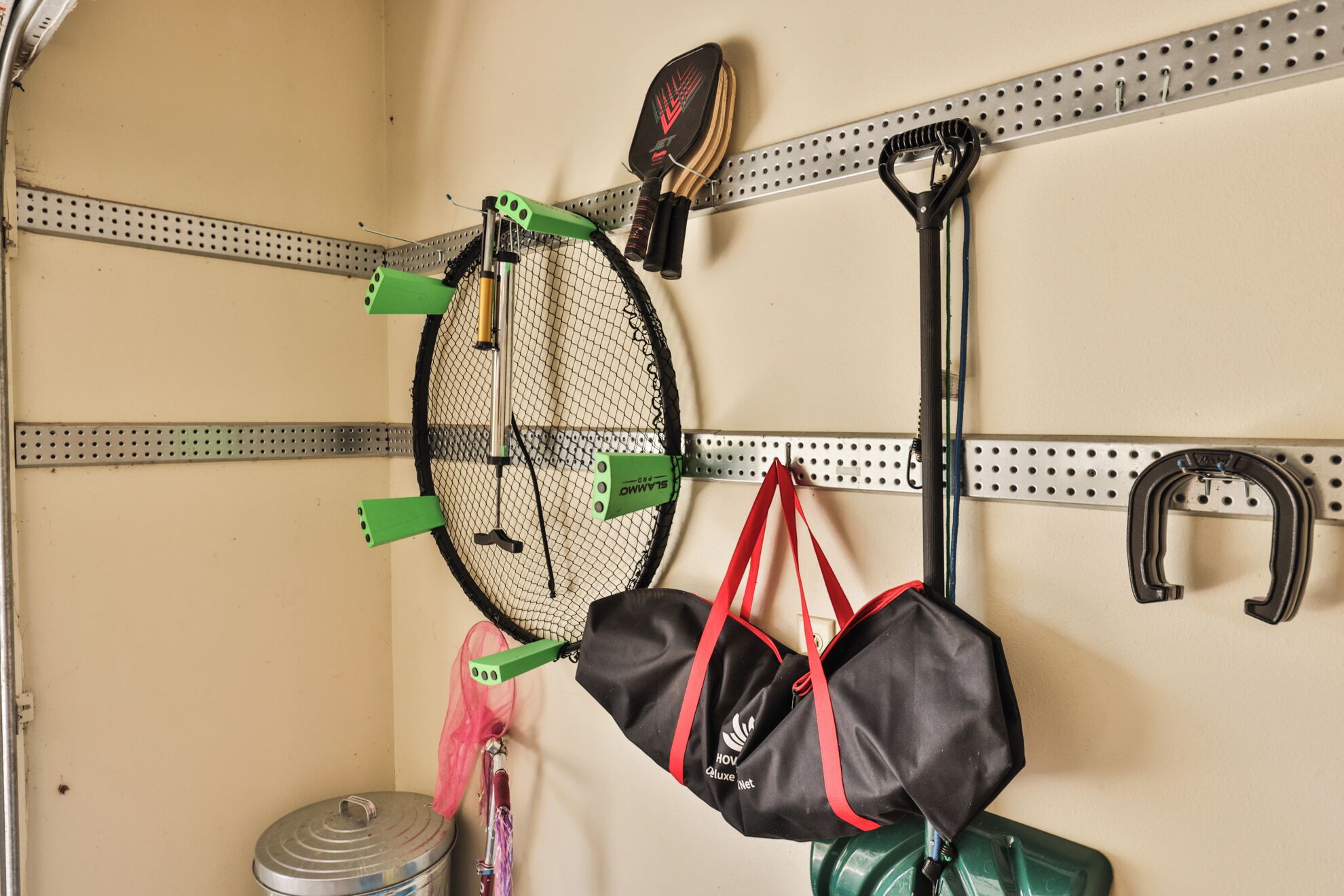 A pegboard with sports equipment, including a tennis racket, a badminton racket, and a badminton shuttlecock.