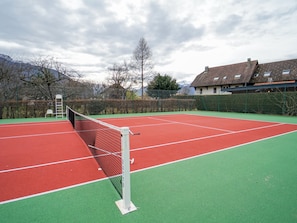 A tennis court with a net, surrounded by a fence and trees. - Le Petit Chalet - Cosy studio in Lathuile for 2 people (Lathuile)