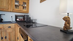A kitchen with wooden cabinets, a black countertop, a microwave, and a decorative wooden sculpture.