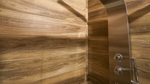 A shower with a curved metallic design and a control panel.