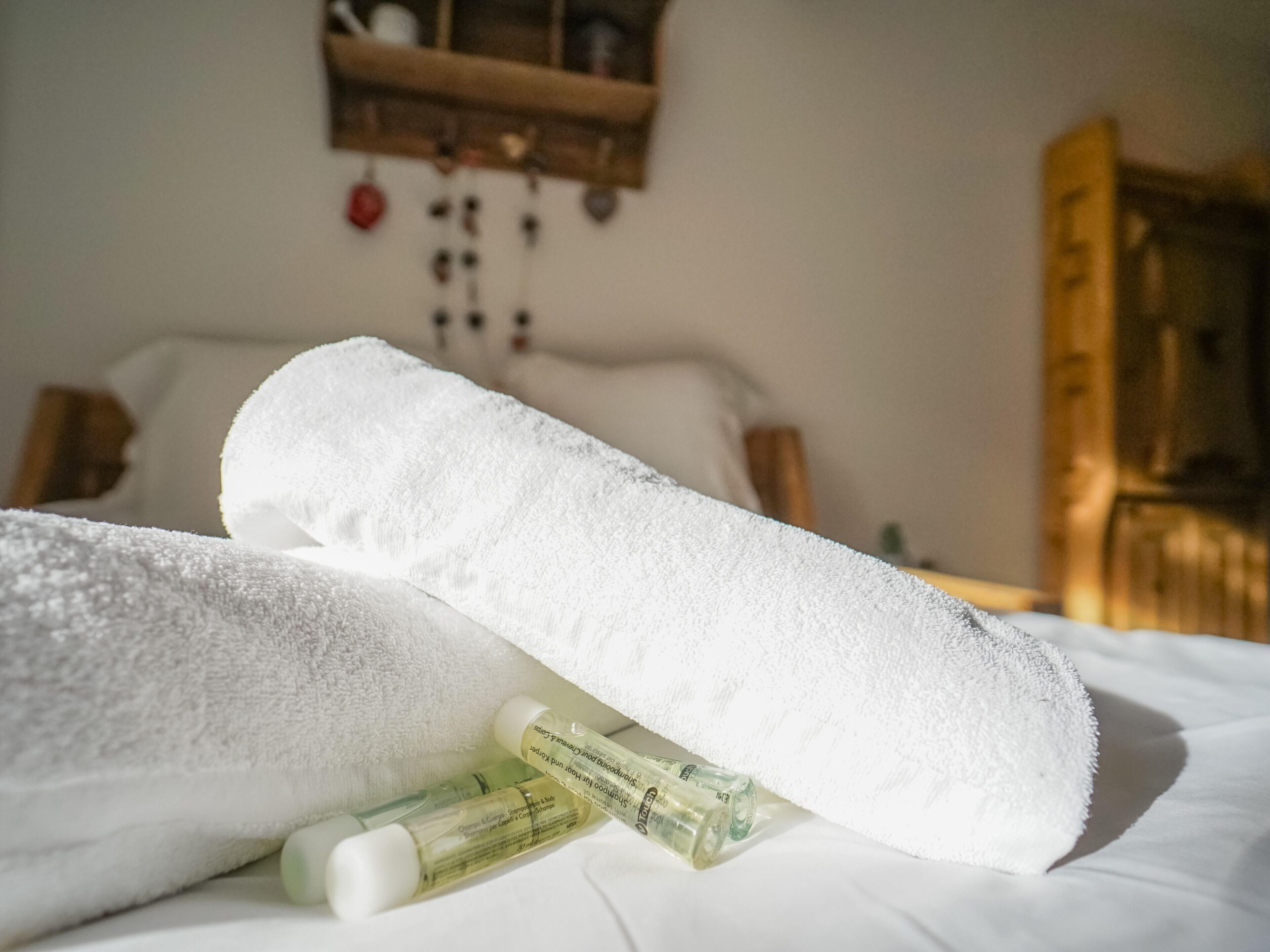 Un lit avec des serviettes blanches et deux bouteilles de lotion posées dessus.