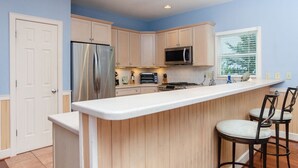 Una cocina con una isla central, un refrigerador, un microondas y un tostador.