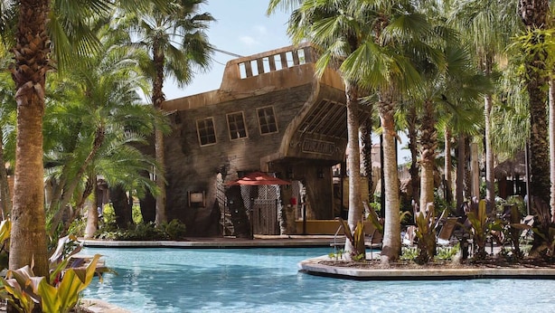 A pool area with a large building featuring arched windows and a sign that reads "TRIBULATION."