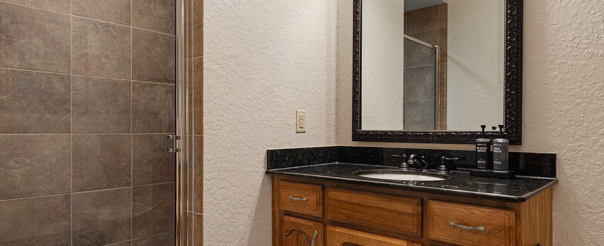 Un baño con ducha, lavamanos y espejo.