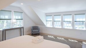 Une chambre à coucher avec un grand lit, une chaise et de nombreuses fenêtres.