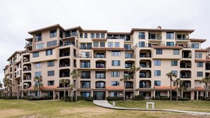 A multi-story hotel with balconies, a central courtyard, and palm trees. - Turtle Dunes #1854 - Ocean Views (amelia island)