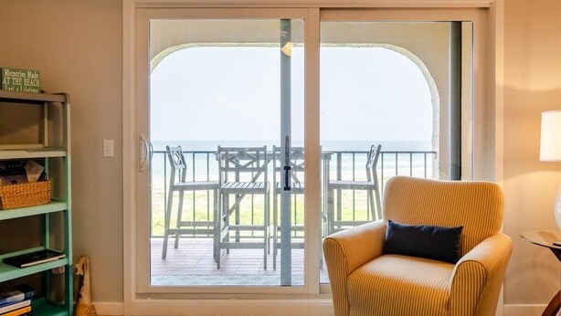 A room with a sliding glass door leading to a balcony with outdoor furniture. - Turtle Dunes #1854 - Ocean Views (amelia island)