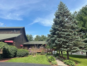 A log cabin with a sloped roof, a red awning, and a wooden deck.