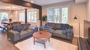 Un salon moderne avec deux canapés, une table basse et une grande fenêtre.