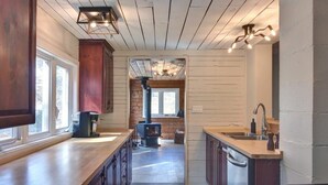 Une cuisine avec des meubles de rangement en bois, une cuisinière encastrée, un évier et une fenêtre.