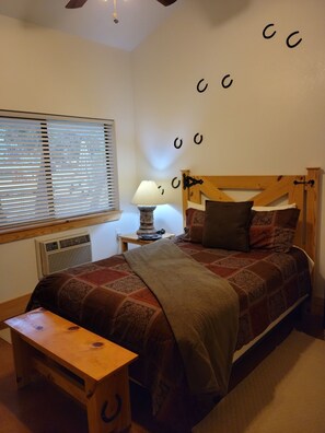 A bedroom with a wooden bed, a bedside table with a lamp, a bench, and a radiator.