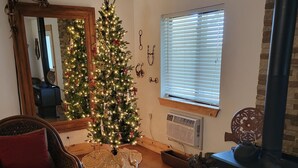 A cozy living room with a Christmas tree, a fireplace, a sofa, and a coffee table.