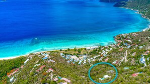 Vista aerea di una zona costiera con spiaggia, case e un mare blu cristallino.