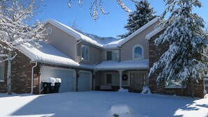 A two-story house with a snow-covered roof and driveway, garage doors, and a front porch. - Fabulous Fully Furnished Vacation Home (Sandy)