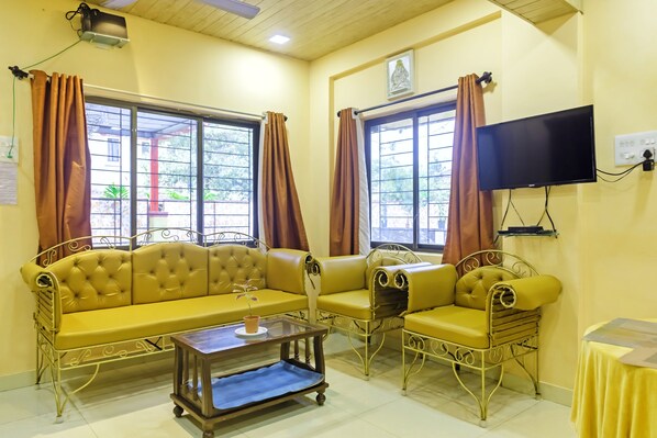 A living room with yellow sofas, a coffee table, and a TV mounted on the wall.