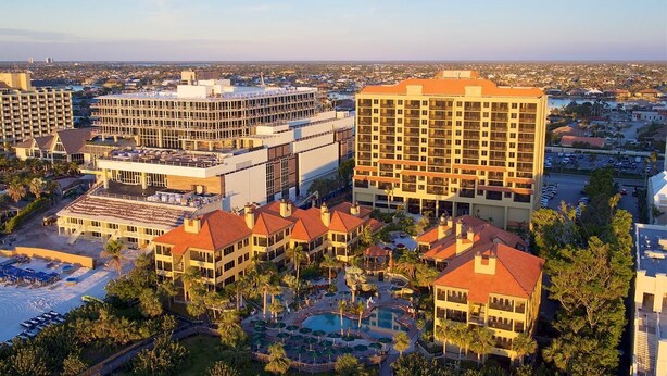 Un complejo turístico con varias edificaciones, una piscina y palmeras.
