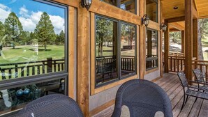 A wooden deck with outdoor seating and large windows overlooking a golf course. - Luxury | Golf Course View | 18th Overlook (Angel Fire)