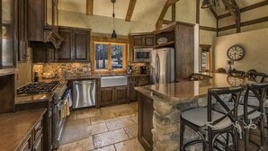 A rustic kitchen with wooden cabinets, a stone countertop, and a built-in stove. - Luxury | Golf Course View | 18th Overlook (Angel Fire)