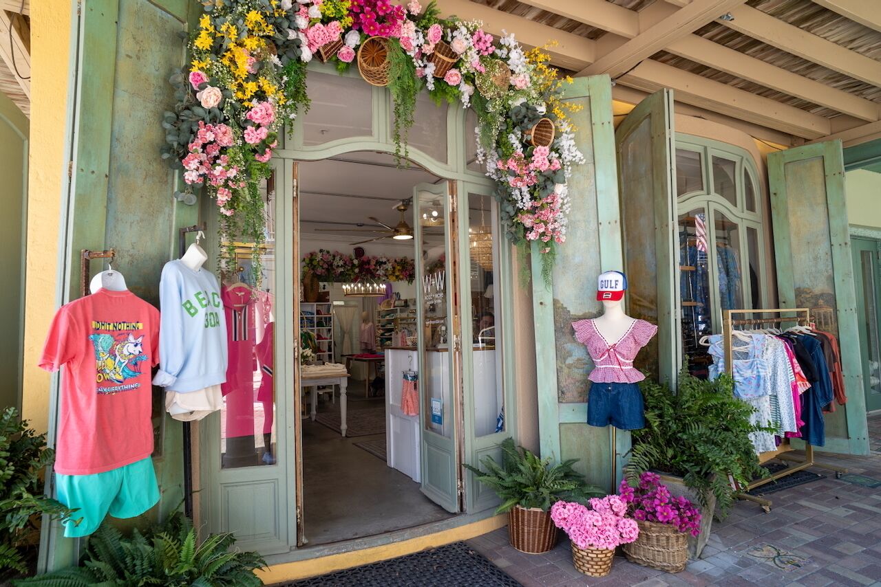 A boutique with a floral archway, mannequins displaying clothing, and a sign indicating 'Gulf'.