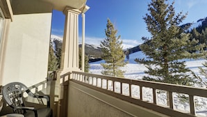 Un balcon donnant sur un paysage montagneux enneigé, avec une chaise et une rambarde.