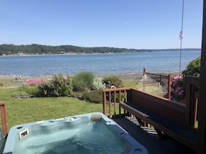 Relax in a serene hot tub on a deck overlooking a peaceful lake.
