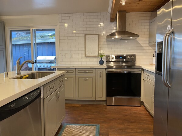 Enjoy cooking in this well-equipped kitchen with a refrigerator, oven, and dishwasher, plus a large window offering a view of the backyard.