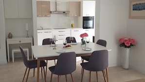 Un espace repas moderne avec une table blanche, quatre chaises et un vase de fleurs.