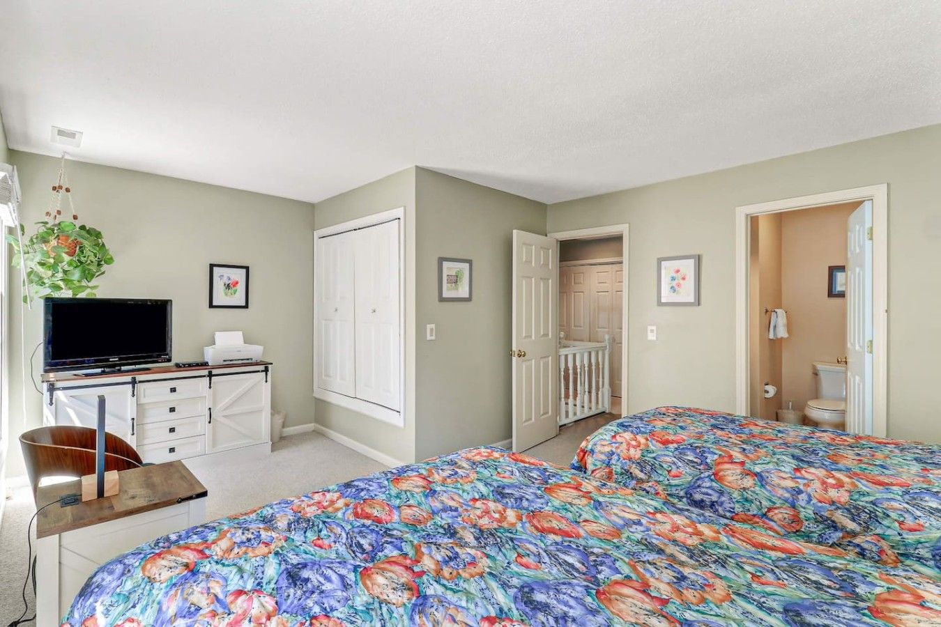 Une chambre avec deux lits, un bureau, une télévision et une porte donnant sur une salle de bain.