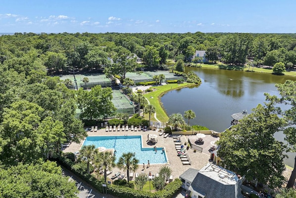 A resort with a swimming pool, tennis courts, and a lake.