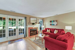 A living room with a fireplace, a red sofa, and a glass coffee table.