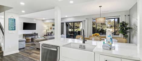 A modern kitchen with a central island, built-in dishwasher, and a dining area with a view.