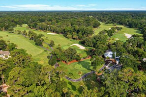 An aerial view of a golf course with multiple greens, sand bunkers, and a clubhouse.