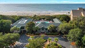 A hotel with a rooftop pool, surrounded by lush greenery and a view of the beach. - Inverness Villa on Golf Course with Pool & Tennis (Hilton Head Island)